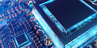 Primo piano di una scheda circuiti elettronica con un microchip al centro, illuminata da un bagliore blu 
