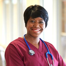Infermiera sorridente con camice bordeaux che indossa uno stetoscopio 3M Littmann Classic III con tubo blu.