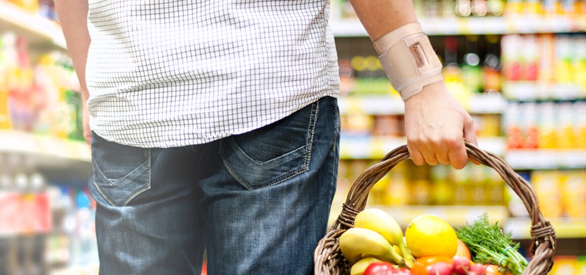 uomo che porta una cesta di frutta indossando uno supporto per il polso