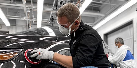 Immagine che mostra un uomo che utilizza abrasivi e strumenti di alta qualità su un'auto per ottenere risultati eccellenti.
