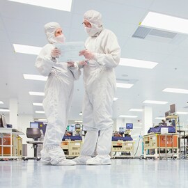 Due persone che indossano dispositivi di protezione e parlano in un laboratorio.