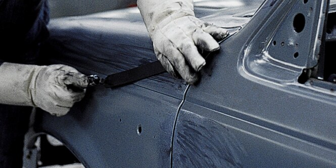 Operatore che ripara un pannello del settore automotive
