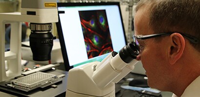 Lo scienziato 3M Mark Tomai mentre guarda al microscopio
