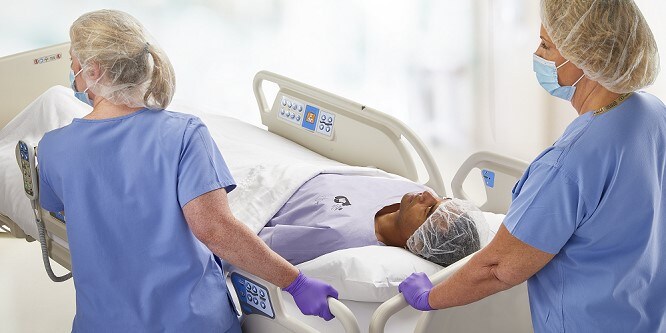 Personale ospedaliero in uniforme spinge il letto di un paziente.
