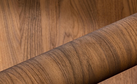 Rotolo di pellicola DINOC con venature del legno su fondo in legno
